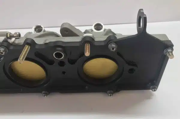 A close-up view of a car engine part with two circular openings on a white background.