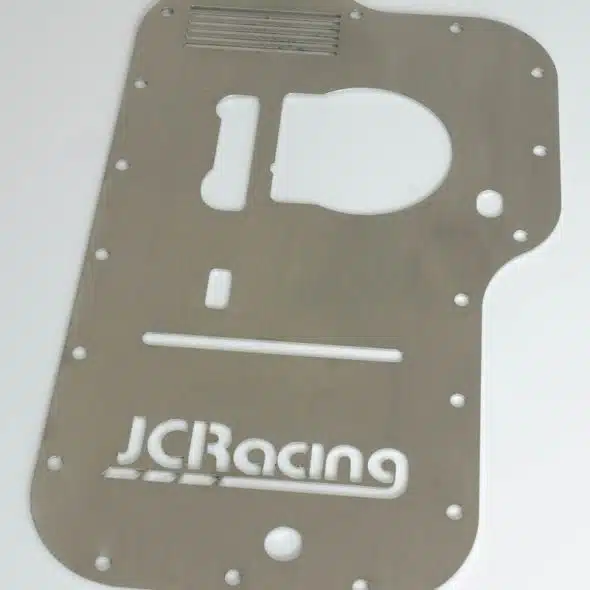 Metal sump baffle plate with cutouts and "JCRacing" logo, placed on a white background.
