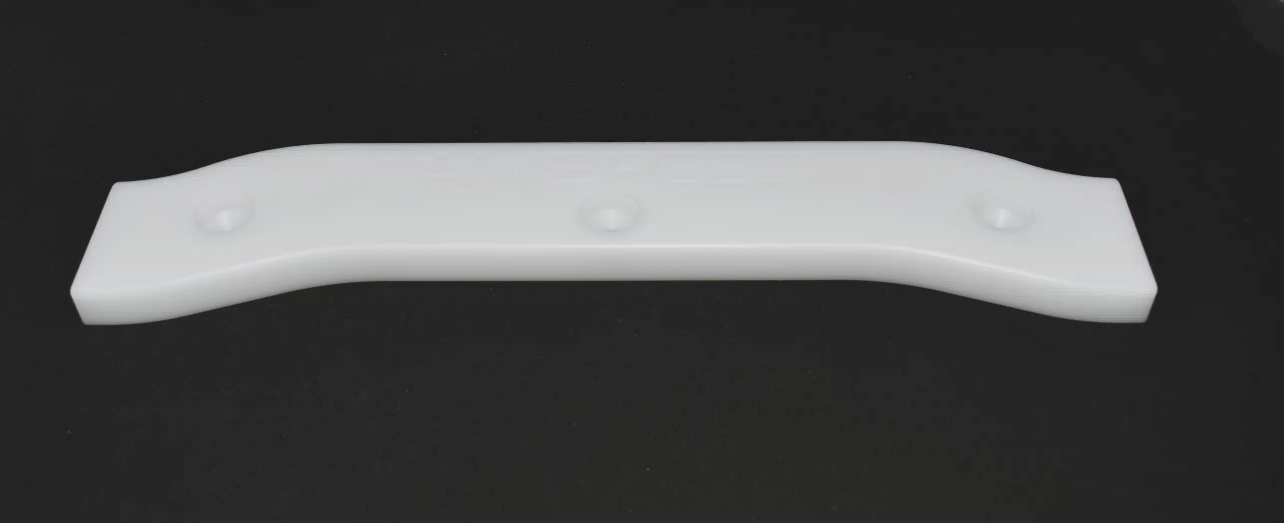 White plastic bracket or handle on a black background.