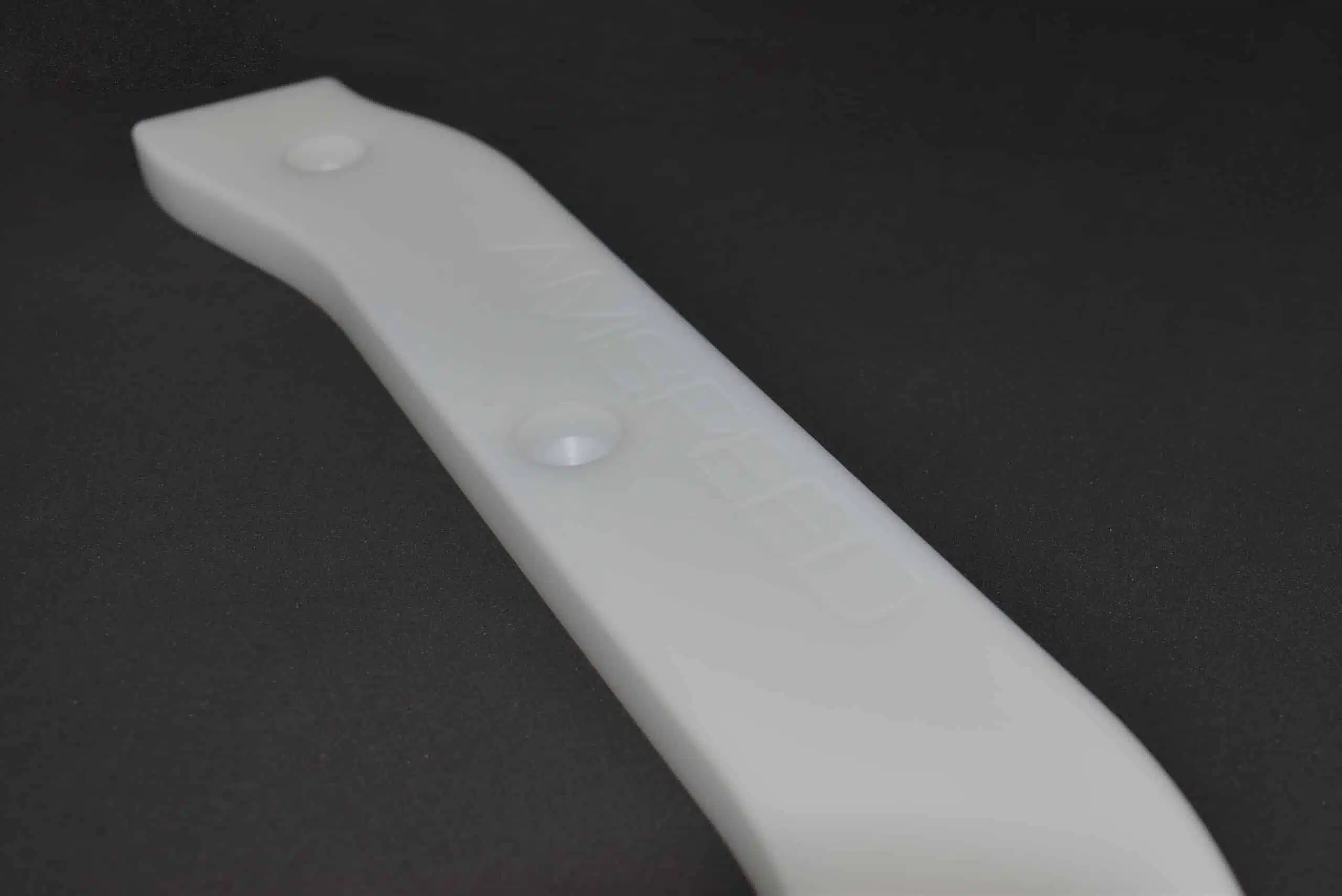 A white plastic blade on a dark background.