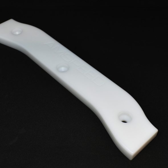 A white plastic strip with three holes, placed on a black background.