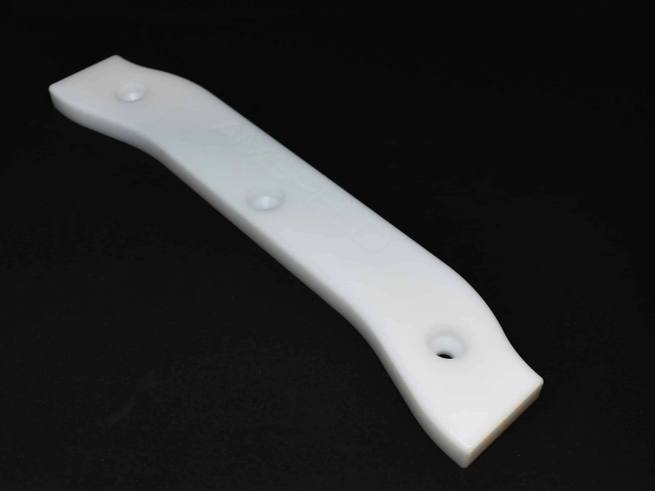 A white plastic strip with three holes, placed on a black background.
