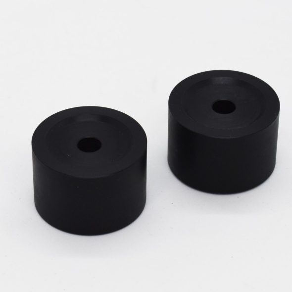 Two black cylindrical rubber stoppers with holes in the center on a white background.