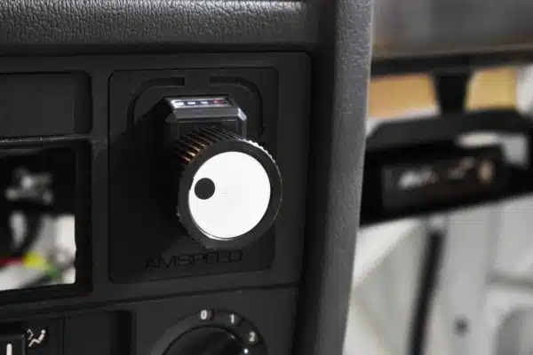 Close-up of a car dashboard showing a control knob with a white face and black markings.