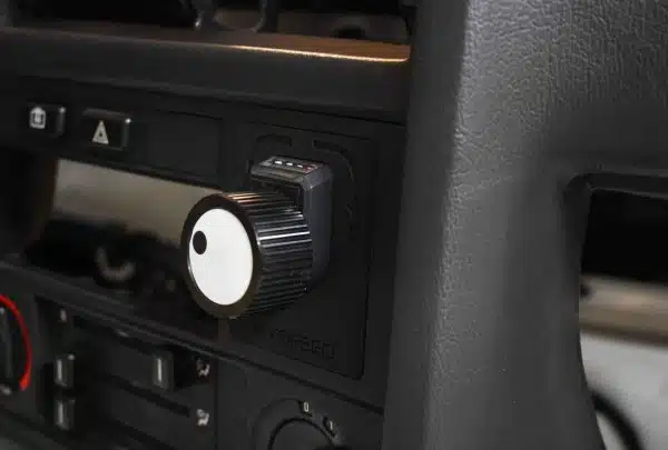 Close-up of a car dashboard with a focus on a black and white control knob.