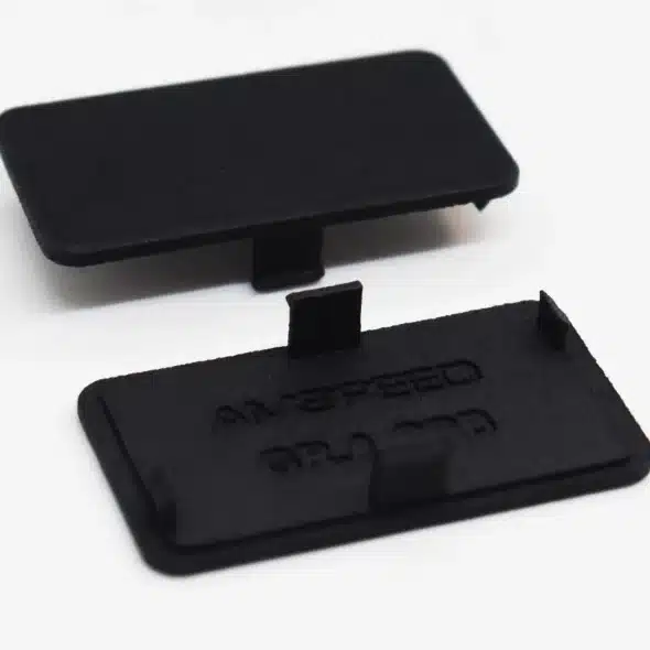 Two black rectangular plastic covers with small clips, placed on a white surface.