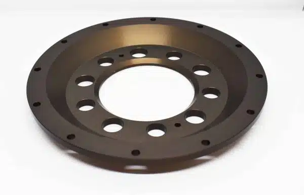 Round metal disk with multiple holes, placed on a white background.