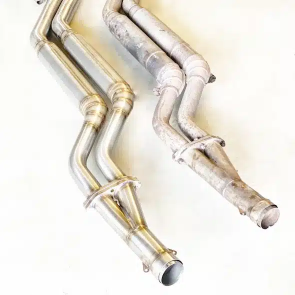 Two exhaust system pipes, one new and shiny, one old and rusty, shown side by side on a white background.