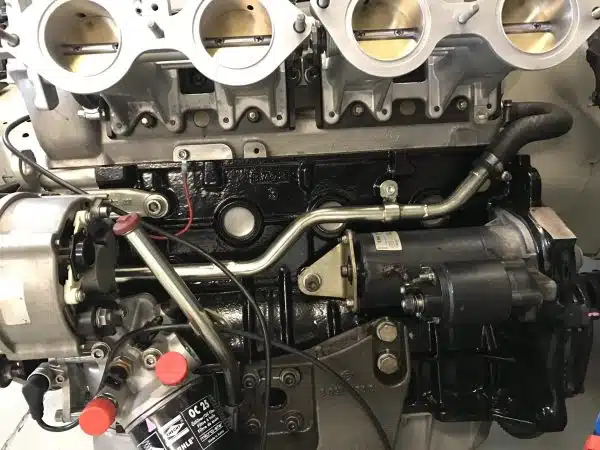 Close-up of a car engine with visible metal parts, wires, and a black starter motor.