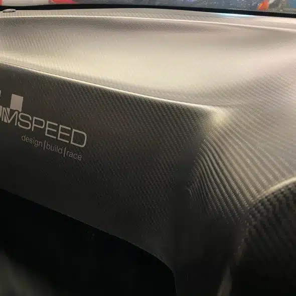 Close-up of a car dashboard wrapped in carbon fiber with the AMPEED logo.
