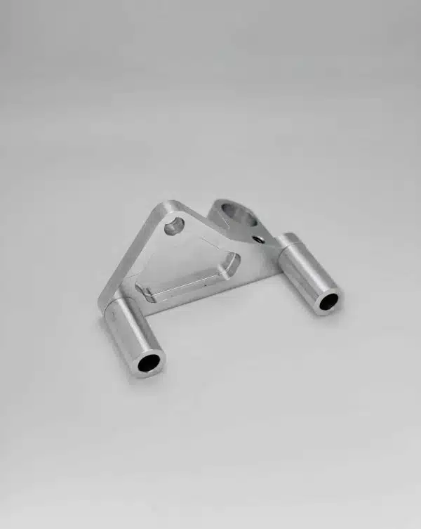 A small metal bracket with two cylindrical arms on a plain light background.
