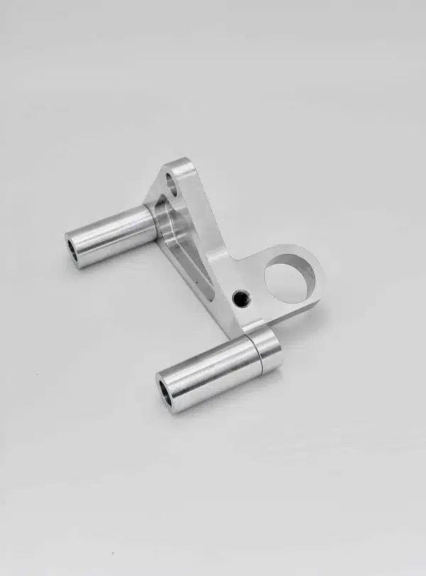 A silver metal bracket with cylindrical ends and a circular hole, placed on a light gray background.