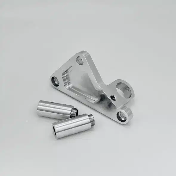 Silver metal bracket and two cylindrical metal parts on a plain white background.