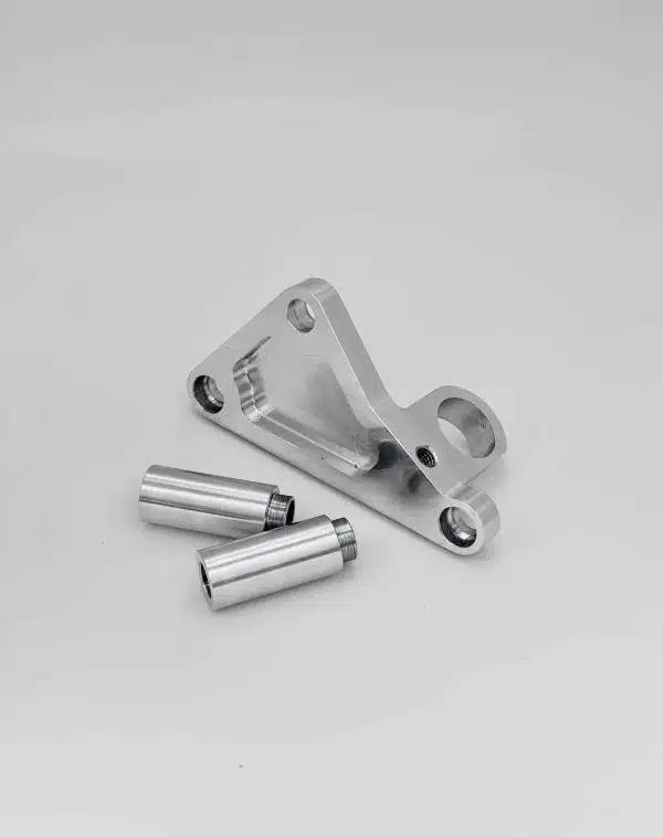 Silver metal bracket and two cylindrical metal parts on a plain white background.