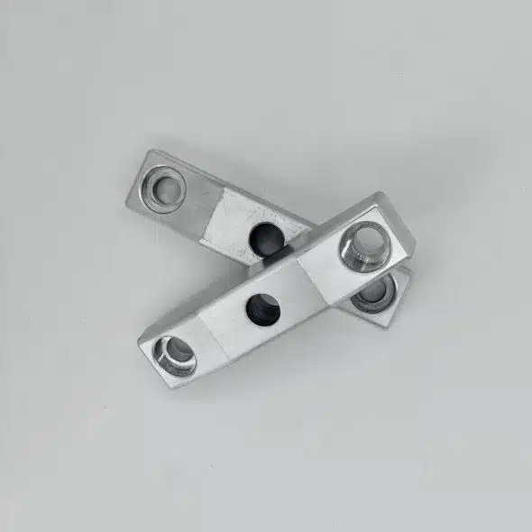 Two silver metal brackets with holes overlap on a plain light gray background.