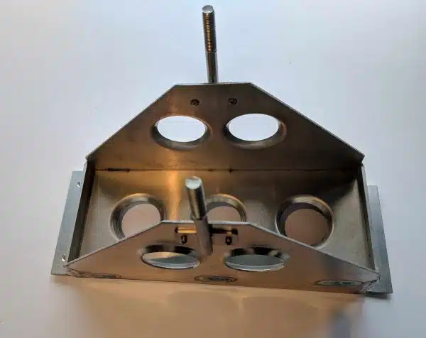 Metal mechanical part with circular holes and two upright rods on a light background.