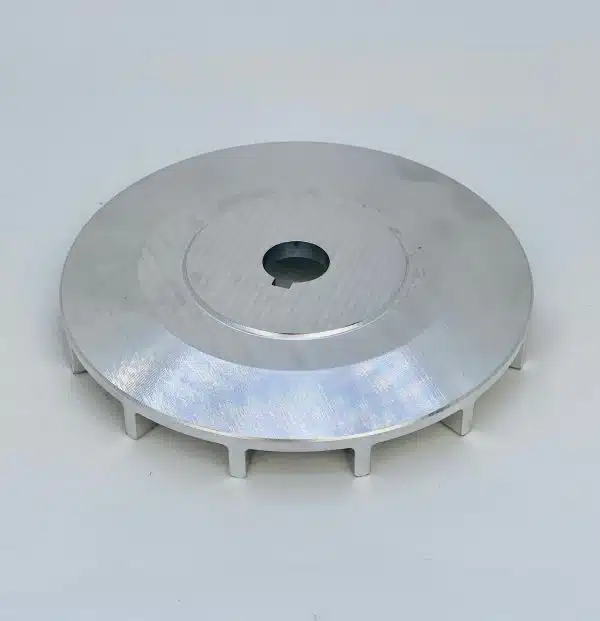 A round metal component with a central hole, resting on a white surface.