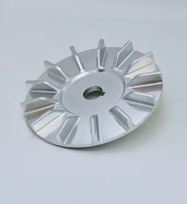 A silver metal turbine or fan blade with a central hole on a plain light background.
