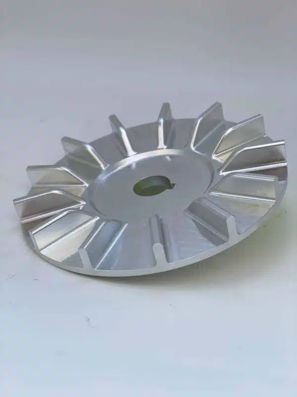 Silver metal fan-shaped component with fins, placed on a light surface.
