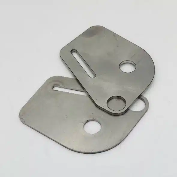 Two metal plates with holes and slots, placed on a white background.