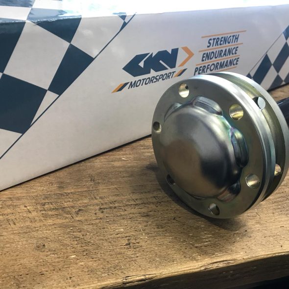 Metal automotive part on a wooden table with a GKN Motorsport box in the background.